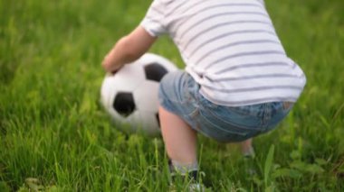 Çocukluk, oyunlar ve eğlence, spor, fiziksel kültür, parklar ve açık hava konsepti - küçük çocuklar ve anneleri güneş batarken parktaki yeşil çimlerde siyah ve beyaz topla futbol oynuyorlar..