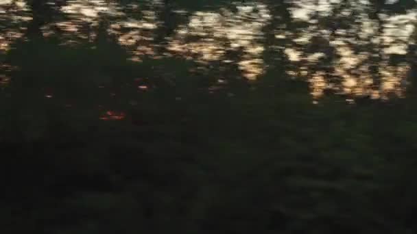 Transport, voyage, route, chemin de fer, paysage, concept de communication - vue de la fenêtre du train à grande vitesse avec éblouissement sur verre au coucher du soleil pour percer les cimes des arbres avant le coucher du soleil en été