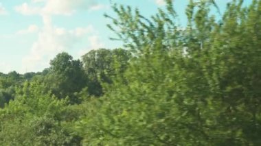 Ulaşım, seyahat, yol, demiryolu, manzara, çiftleşme konsepti - bulutlu aydınlık bir günde doğanın ve ormanın güzel çayırlarının manzarası üzerinde hız treninin penceresinden manzara