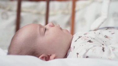 bebeklik, çocukluk, gelişim, tıp ve sağlık konsepti - yeni doğmuş çıplak, canlı, şakacı bebek suratları beyaz arka plandaki beşiğinde uzanan oyuncaklara uzanır