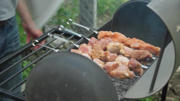 Cafés e restaurantes, culinária, piquenique, conceito de cozinha oriental - carne de porco close-up e kebab de frango amarrado em espeto defumado e frito em grelha em carvão assado. mens mão de calor com onda sob churrasco — Vídeo de Stock