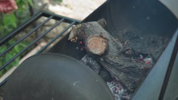 Кулінарія, східна кухня, лісові пожежі, концепція підпалу - освітлення вогню та вугілля в чорному металевому грилі для куріння та смаження м'яса та овочевої їжі в спеку дикої природи з димом . — стокове відео