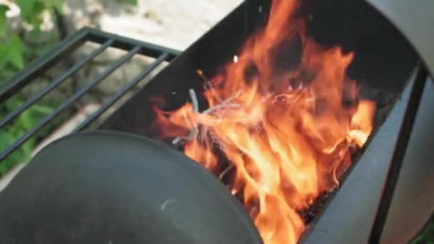 Kochen, orientalische Küche, Waldbrände, Brandschutzkonzept - Anzünden von Feuer und Kohlen in schwarzem Metallgrill zum Räuchern und Braten von Fleisch und Gemüse in der Hitze der Wildtiere im Freien mit Rauch. — Stockvideo