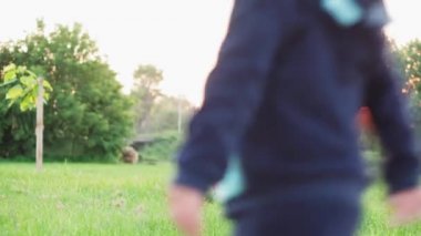 Çocukluk, oyunlar ve eğlence, spor, fiziksel kültür, parklar ve açık hava konsepti - küçük çocuk ve kız ikizler aynı yaşta acemice parktaki parlak yeşil çimlerde uçan diskle oynuyorlar gün batımında