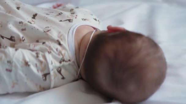 Säuglings-, Kindheits-, Entwicklungs-, Medizin-und Gesundheitskonzept - Nahaufnahme Gesicht des Neugeborenen nackt wach schlafenden vier Monate alten Baby Grimassen auf Bauch liegend auf weißem Hintergrund — Stockvideo