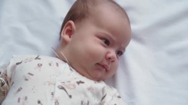 bebeklik, çocukluk, gelişim, tıp ve sağlık konsepti - yeni doğmuş çıplak, uyanık, neşeli bebek buruşuklukları beyaz arka plandaki beşikte uzanan oyuncaklara uzanır