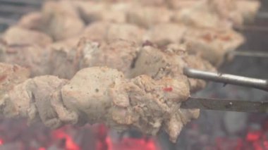 Kafeler ve restoranlar, yemek pişirme, piknik, doğu mutfağı konsepti yakın plan domuz eti ve kızarmış kömürde ızgarada kızartılmış tavuk kebabı. Açık havada mangal yapan adamın eli kapağı kapatır.