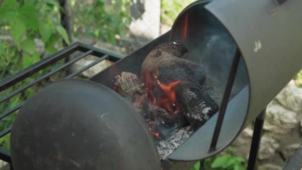 Koken, oosterse keuken, bosbranden, brandstichting concept - vuur en kolen in zwart metalen rooster voor het roken en bakken van vlees en groente voedsel in de hitte van de natuur met rook. — Stockvideo