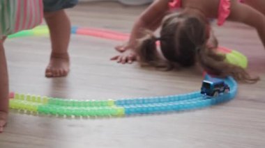 Çocukluk, oyunlar, yetiştirme ve geliştirme konsepti - küçük çocukların genel planı aynı yaşta erkek ve kız çocuklarının oyun odasında oyuncak motorlu arabalarla yarış pisti yapımcılarıyla oynuyorlar.