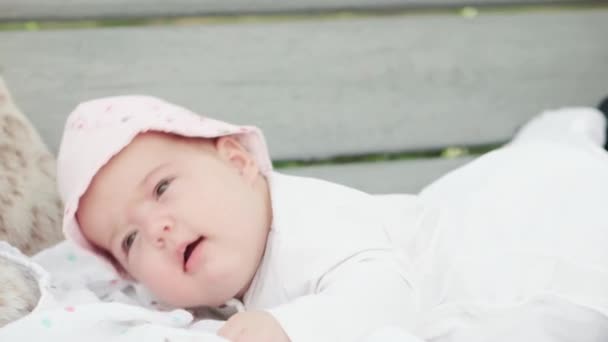 Säuglingsalter, Kindheit, Entwicklung, Sommerurlaub, Medizin und Gesundheitskonzept - Nahaufnahme Porträt eines wachen neugeborenen Mädchens im Alter von fünf Monaten, das auf dem Bauch auf einer Schaukelbank in panamaischen lächelnden Outdor liegt — Stockvideo