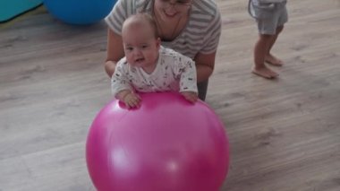 Çocukluk, annelik, oyunlar, yetiştirme ve geliştirme konsepti - yakın plan genç anneler spor yapıyor ve masah yaparken iki yeni doğan ve küçük kız çocuk oyun odasında gülümsüyor.