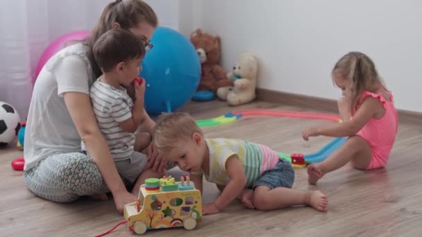 Enfance, jeux, concept d'éducation et de développement - plan général des jeunes enfants garçon et fille du même âge avec maman jouent avec des enfants constructeur de voitures en bois et des puzzles dans la salle de jeux pour enfants — Video