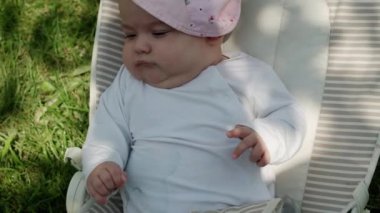 bebeklik, çocukluk, gelişme, yaz tatili, tıp ve sağlık konsepti - Beş aylık uyanık bebek bebek portresi yeşil çimenlerin arka planında sallanan sandalyede yatıyor