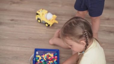 Çocukluk, annelik, oyunlar, terbiye ve gelişim konsepti - yakın plan geniş anne, çocuk oyun odasında yeni doğmuş küçük kız ve erkek çocuk aynı yaşta çok renkli mozaiklerle neşe içinde oynuyor
