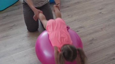 Çocukluk, annelik, oyunlar, yetiştirme ve geliştirme konsepti - genel plan genç anne spor yapıyor ve üç yaşındaki küçük kızıyla spor yapıyor ve çocuk oyun odasında gülümsüyor.