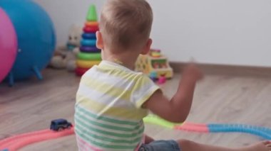 Çocukluk, oyunlar, yetiştirme ve geliştirme konsepti - küçük çocukların genel planı aynı yaşta erkek ve kız çocuklarının oyun odasında oyuncak motorlu arabalarla yarış pisti yapımcılarıyla oynuyorlar.