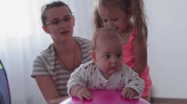 Çocukluk, annelik, oyunlar, yetiştirme ve geliştirme konsepti - yakın plan genç anneler spor yapıyor ve masah yaparken iki yeni doğan ve küçük kız çocuk oyun odasında gülümsüyor.