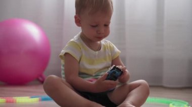 Çocukluk, oyunlar, yetiştirme ve geliştirme konsepti - küçük çocukların genel planı aynı yaşta erkek ve kız çocuklarının oyun odasında oyuncak motorlu arabalarla yarış pisti yapımcılarıyla oynuyorlar.