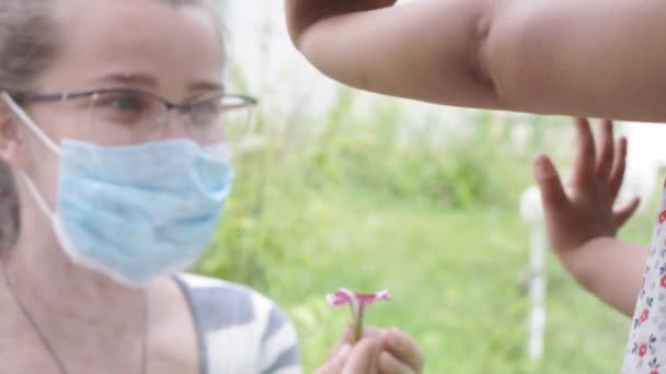 의료용 마스크를 착용하고 있는 엄마는 코로나 바이러스 (coronavirus) 때문에 격리중인 아기를 창밖을 내다본다. 자립심. 클로즈업. — 비디오