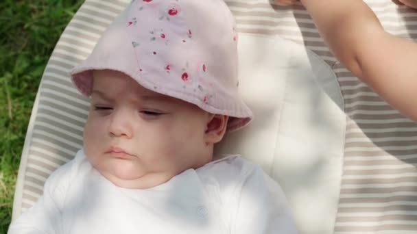 Infância, infância, desenvolvimento, férias de verão, medicina e conceito de saúde - Close-up top view retrato de bebê recém-nascido acordado menina de cinco meses de idade deitado em fundo cadeira de balanço de grama verde — Vídeo de Stock