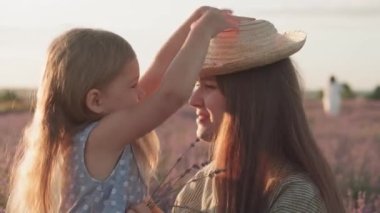 Geniş aile, babalık, çocukluk, annelik, provence tarzı konsept - mutlu genç anne ve küçük kız gün batımından önce lavanta tarlasında öpüşüp gülüyorlar.
