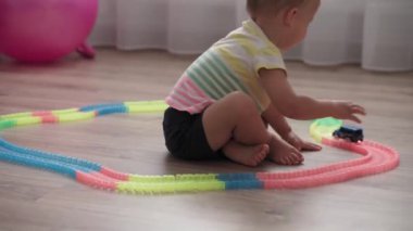 Çocukluk, oyunlar, yetiştirme ve geliştirme konsepti - küçük çocukların genel planı aynı yaşta erkek ve kız çocuklarının oyun odasında oyuncak motorlu arabalarla yarış pisti yapımcılarıyla oynuyorlar.