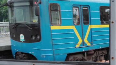 Şehir ulaşımı, seyahat, altyapı, metropol konsepti. Dinyeper Nehri üzerindeki bir köprüden mavi ve sarı bir metro geçiyor..
