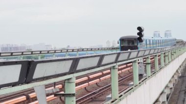 Şehir ulaşımı, seyahat, altyapı, metropol konsepti. Dinyeper Nehri üzerindeki bir köprüden mavi ve sarı bir metro geçiyor..