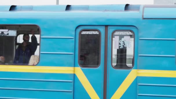 Transporte público urbano, viajes, infraestructura, concepto de metrópolis: un metro azul y amarillo pasa a través de una estación de tierra en un puente sobre el río Dniéper. — Vídeo de stock