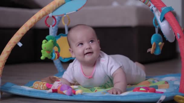 Infancy, childhood, development, summer holiday, lifestyle concept - Close up of happy cute newborn kid 5 month of age laying on floor developing mat Activity Gym baby doing tummy time with toy inside — Stock Video