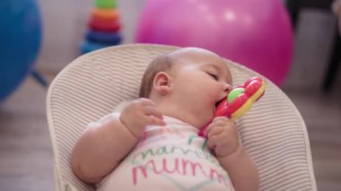 bebeklik, çocukluk, gelişme, yaz tatili, tıp ve sağlık konsepti - 5 aylık uyanık bebek bebek portresinin yakın çekimi oyuncak teether ile sallanan sandalyede yatıyor