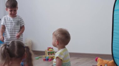 Çocukluk, oyunlar, yetiştirilme ve gelişim konsepti - annesiyle aynı yaşta küçük çocukların genel planı çok renkli yüzük piramidiyle oynamak bebek oyun odasında üzgün ağlıyor