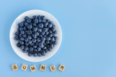 meyve ve sebze, vitamin, sağlıklı yiyecek ve içecek, geleneksel tıp, gastronomi konsepti - beyaz tabakta mor böğürtlen yerleşimi ve mavi arkaplan fotokopi alanı üzerine yazı