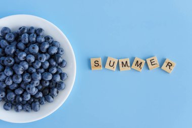 meyve ve sebze, vitamin, sağlıklı yiyecek ve içecek, geleneksel tıp, gastronomi konsepti - beyaz tabakta mor böğürtlen yerleşimi ve mavi arkaplan fotokopi alanı üzerine yazı