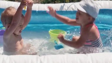 Avrupa 'da aynı yaşta iki küçük çocuk yazın havuzda banyo yapıp eğleniyorlar, su sıçratıyorlar, yaşam tarzı tasarımı yapıyorlar. Aktivite doğa eğlencesi. Yavaş çekim