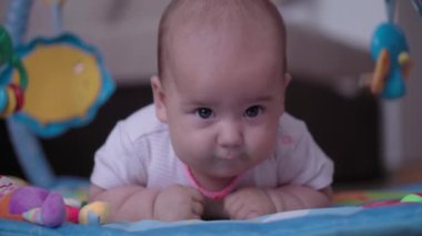 Bebeklik, çocukluk, gelişme, yaz tatili, yaşam tarzı konsepti - 5 aylık paspasın üzerinde yatıp karnını oyuncaklarla doyuran mutlu, yeni doğmuş çocuğun kapanışı