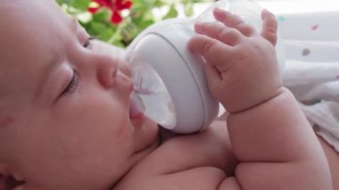 bebeklik, çocukluk, yaz tatili, tıp ve sağlık konsepti - 5 aylık sallanan sandalyede uzanmış, emzik ile şişeden içen uyanık bebek portresi