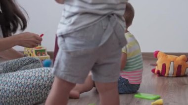Çocukluk, oyunlar, yetiştirilme ve gelişim konsepti - annesiyle aynı yaşta küçük çocukların genel planı çocuk oyun odasında gökkuşağı renginde çok renkli halkalar piramidiyle oynuyor