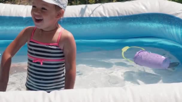 같은 나이의 어린 두 어린이와 캅카스 유럽 슬라브인 소녀가 여름에 수영장에서 물을 뿌리고 생활 방식을 설계하며 행복하게 목욕을 하고 있다. 활동성 자연여가. 느린 동작 — 비디오