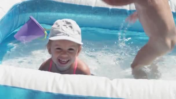 Dvě malé děti chlapec a dívka kavkazský evropský slovanský vzhled ve stejném věku jsou šťastný koupel a hýčkat v bazénu v létě, stříkající vody, životní styl designu. Činnost příroda volný čas. Zpomalený pohyb — Stock video