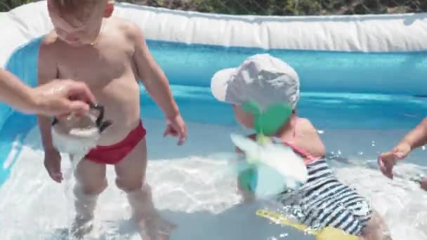 Due bambini piccoli ragazzo e ragazza caucasico aspetto slavo europeo della stessa età sono bagno felice e giocherellare in piscina in estate, spruzzi d'acqua, stile di vita design. Attività natura tempo libero. Rallentatore — Video Stock