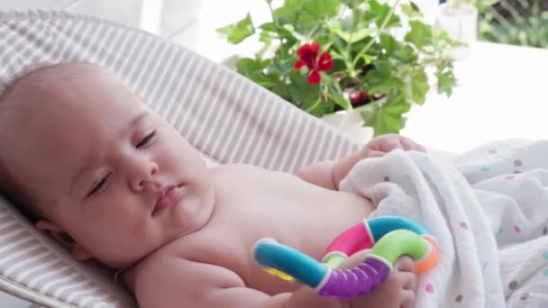 Младенчество, детство, развитие, летние каникулы, медицина и концепция здоровья - Крупный план портрет бодрствующей новорожденной девочки в возрасте пяти месяцев, лежащей в кресле-качалке — стоковое видео