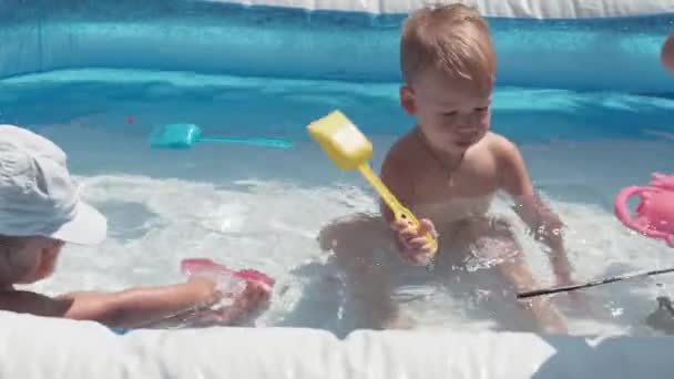 Aynı yaştaki 3 küçük çocuk ve kız çocuğu, Avrupa 'da aynı yaşta olan Kafkas Slav görünümlü mutlu bir şekilde havuzda yıkanıp eğleniyorlar, su sıçratarak, yaşam tarzı tasarlayarak. Aktivite doğa eğlencesi. Yavaş çekim — Stok video