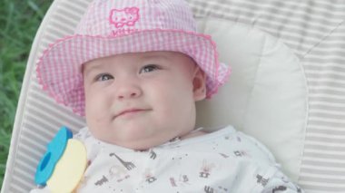 bebeklik, çocukluk, gelişme, yaz tatili, tıp ve sağlık konsepti - Beş aylık uyanık bebek bebek portresi yeşil çimenlerin arka planında sallanan sandalyede yatıyor