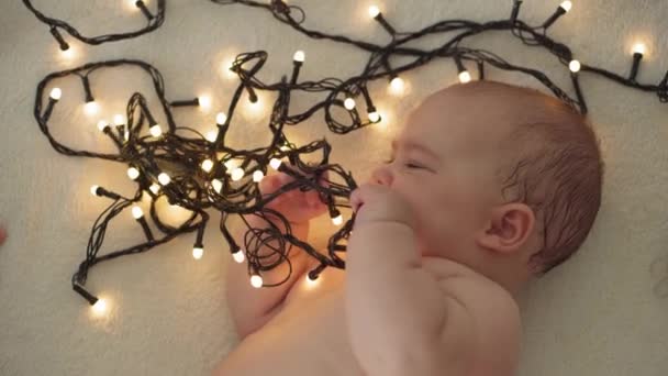 Boldog karácsonyt és boldog új évet, csecsemők, gyermekkor, ünnepek koncepció - közelkép meztelen 6 hónapos újszülött baba télapó claus kalap hasán kúszik díszek karácsonyfa. — Stock videók