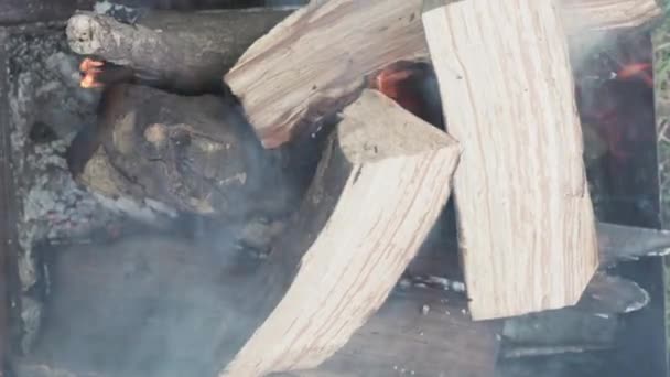 Cuisine, cuisine orientale, feux de forêt, incendie criminel concept - allumage du feu et des charbons dans un grill métallique noir pour fumer et frire de la viande et des aliments végétaux en chaleur de fond extérieur de pierres blanches — Video