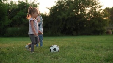 Çocukluk, oyunlar ve eğlence, spor, fiziksel kültür, açık hava konsepti - küçük çocuklar el ele tutuşup uçağın gün batımında parktaki açık yeşil çimlerde koşup düşüşünü tasvir ediyorlar.