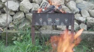 Yemek pişirme, doğu mutfağı, orman yangınları, kundakçılık kavramı - beyaz taşların arka planında sigara içmek ve et ve sebze kızartmak için siyah metalik ızgarada ateş ve kömür yakmak