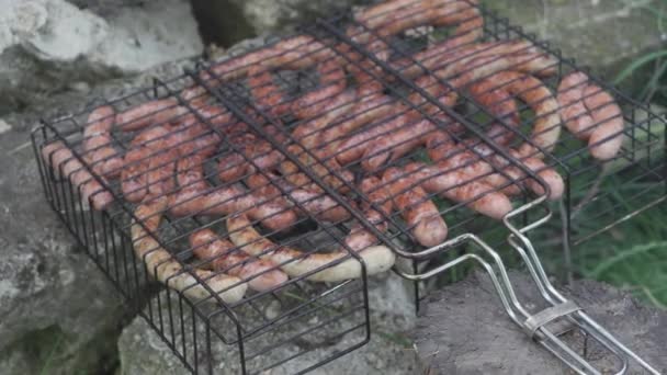 Cafés y restaurantes, cocina, picnic, concepto de cocina oriental primeros planos embutidos en la parrilla de barbacoa encadenado en pincho ahumado y frito sobre brasas asadas. Mano de hombre al aire libre se prepara para comer. — Vídeo de stock