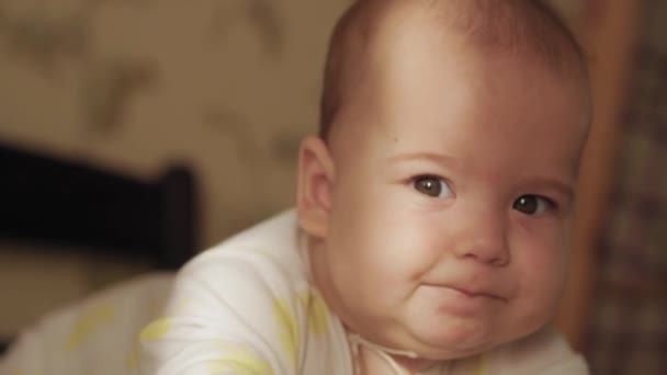 Infância, infância, desenvolvimento, medicina e conceito de saúde - primeiro plano do recém-nascido nu dormindo acordado 6 meses de idade caretas de bebê deitado no estômago com um raio de sol brilhante no rosto pela manhã — Vídeo de Stock